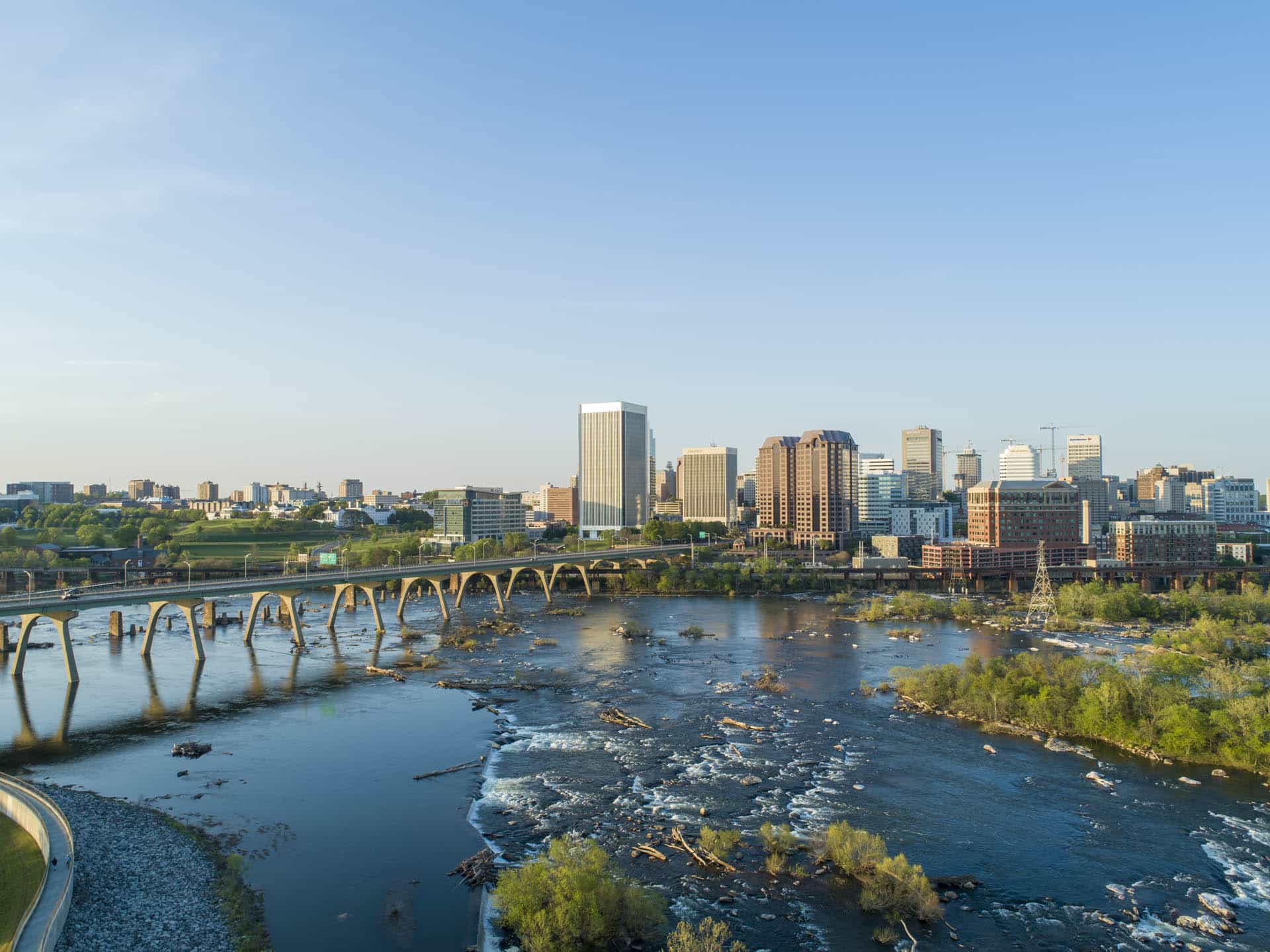 Aerial view of downtown Richmond, Virginia with the James River and bridge in the foreground.