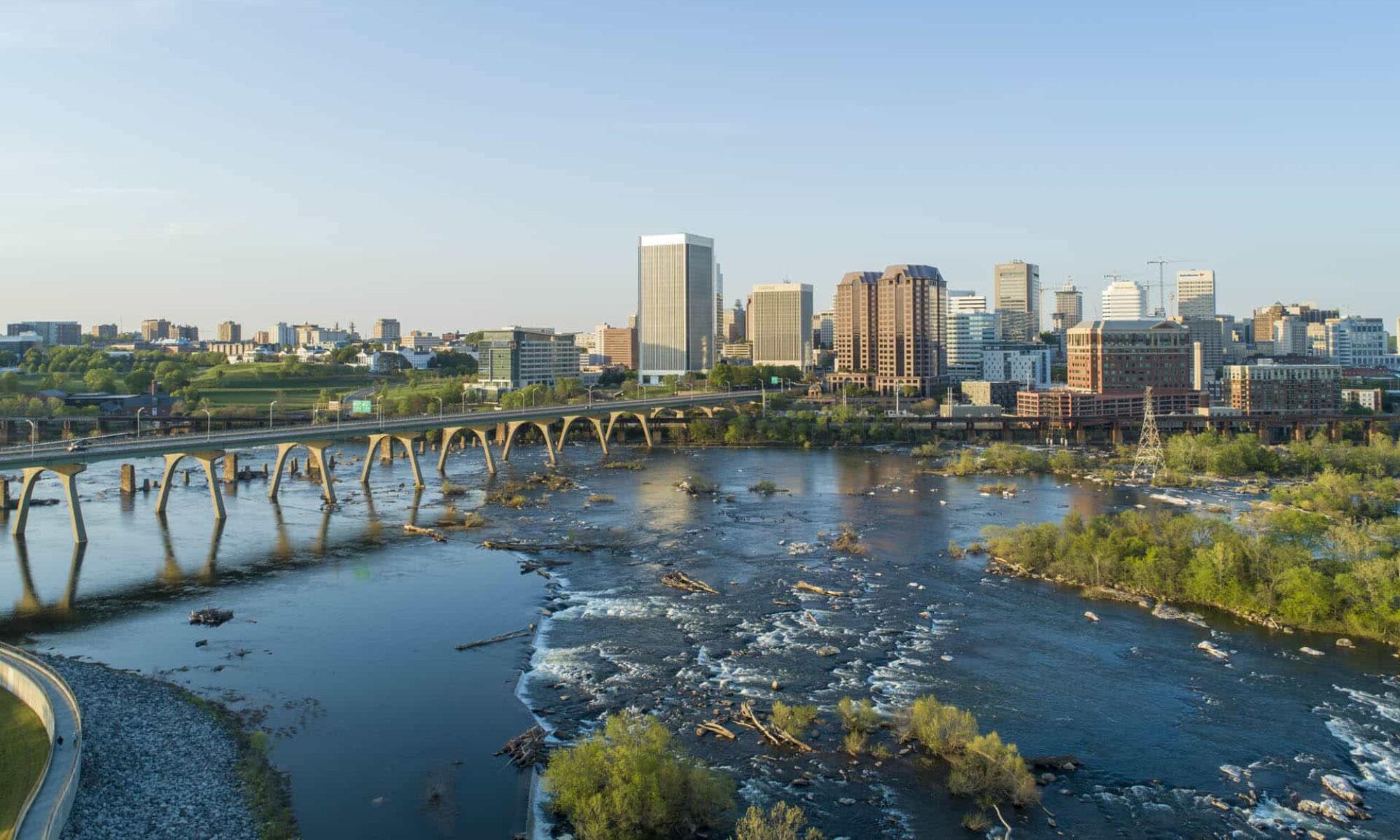 Aerial view of downtown Richmond, Virginia with the James River and bridge in the foreground.